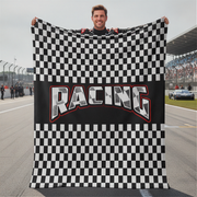 Person holding a checkered racing flag with 'Racing' text on a race track.