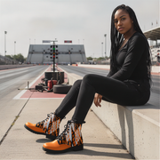 Woman sitting in a drag track wearing a checkered pattern orange boots