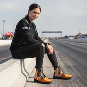 Woman sitting in a drag track wearing a checkered pattern orange boots