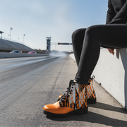 Woman sitting in a drag track wearing a checkered pattern orange boots