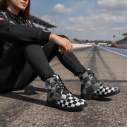 Person sitting on a race track wearing checkered boots