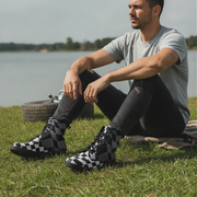 Man sitting by a lake wearing checkered boots