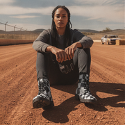 Woman sitting on a dirt track wearing checkered boots
