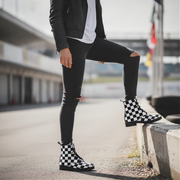 Person wearing black checkered boots on a road with blurred background