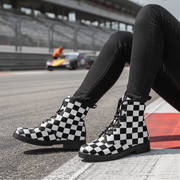 Person wearing checkered boots on a race track with a car in the background