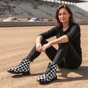 Woman sitting on a race track wearing black and white checkered boots.