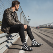Man sitting on a race track wearing checkered boots