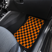 A pair of car floor mats with a black and orange checkerboard pattern, shown installed in the front passenger and driver footwells of a dark gray car.