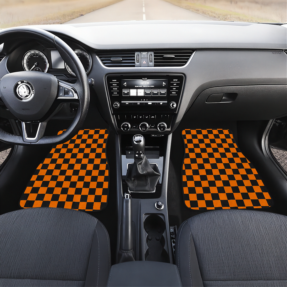 A pair of black and orange checkered car floor mats installed in the front of a car interior, shown from a top-down perspective with the dashboard, steering wheel, and center console visible.