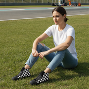 Woman sitting on grass wearing checkered shoes with a race track in the background