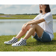 Woman sitting on grass wearing checkered shoes with a scenic background