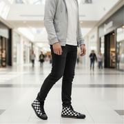 Person wearing a gray hoodie, black jeans, and checkered shoes in a mall setting