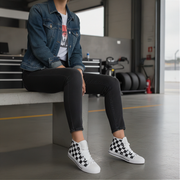 Woman wearing checkered shoes sitting on a bench in an industrial setting