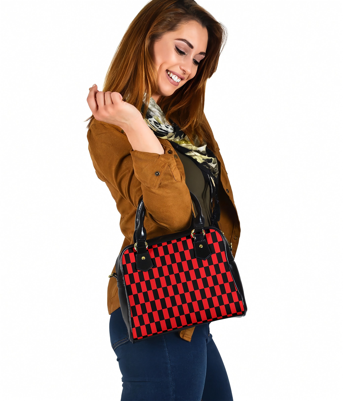 A woman wearing a brown jacket and blue jeans holds a red and black checkered handbag against a plain white background.