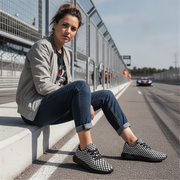 Woman sitting on a race track wearing checkered shoes