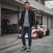 Man standing in front of a racing car on a track wearing checkered sneakers
