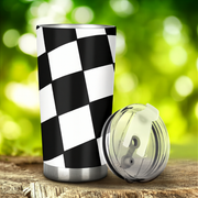 Checkered pattern tumbler with a clear lid on a wooden surface with a green blurred background