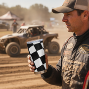 Man holding a checkered tumbler with off-road vehicle in the background