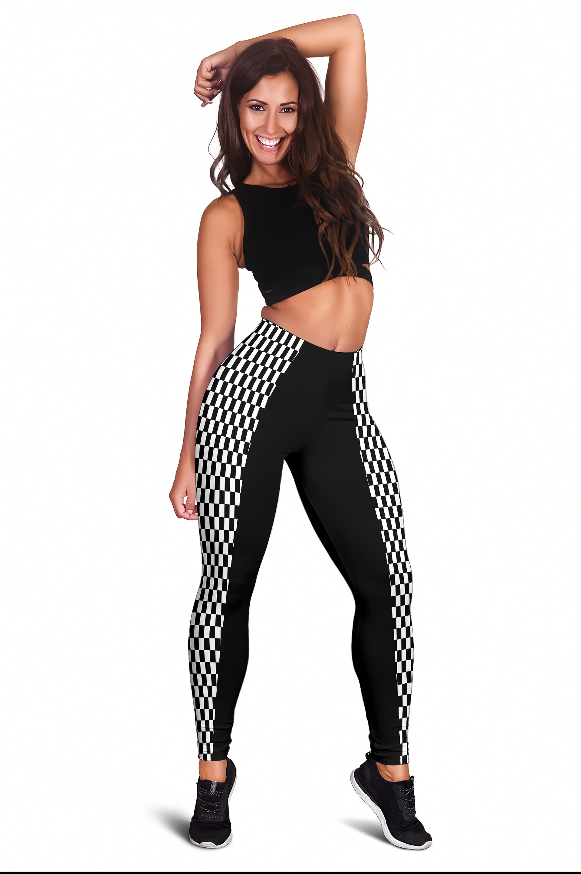 A woman modeling high-waisted black leggings with a black and white checkered side stripe, paired with a black crop top and black sneakers, against a plain white background.