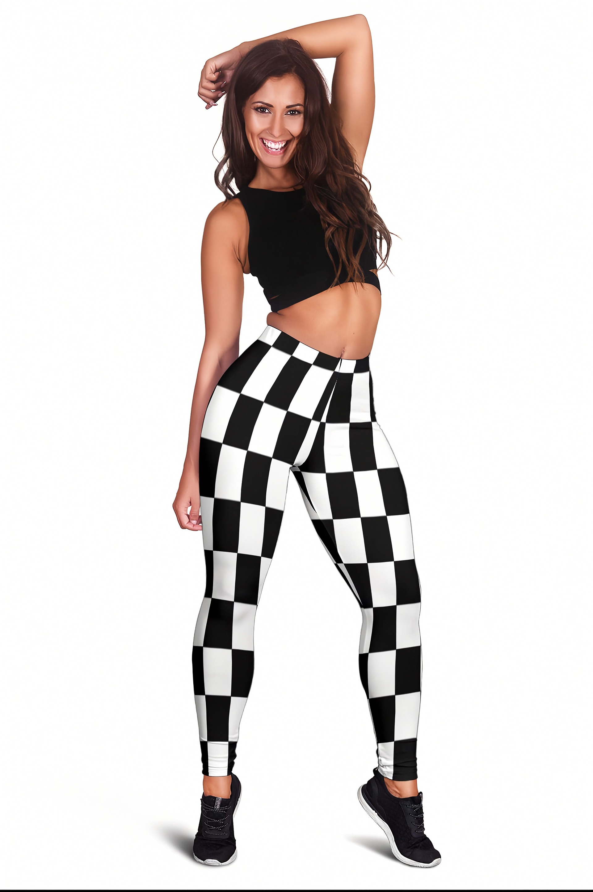 A woman modeling high-waisted leggings with a bold black and white checkerboard pattern, paired with a black crop top and black sneakers, set against a plain white background.