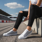 Woman wearing checkered shoes sitting on a race track.