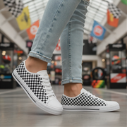 Person wearing black and white checkered sneakers with light blue jeans in a mall setting.