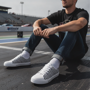 Man wearing checkered low top shoes sitting on a race track