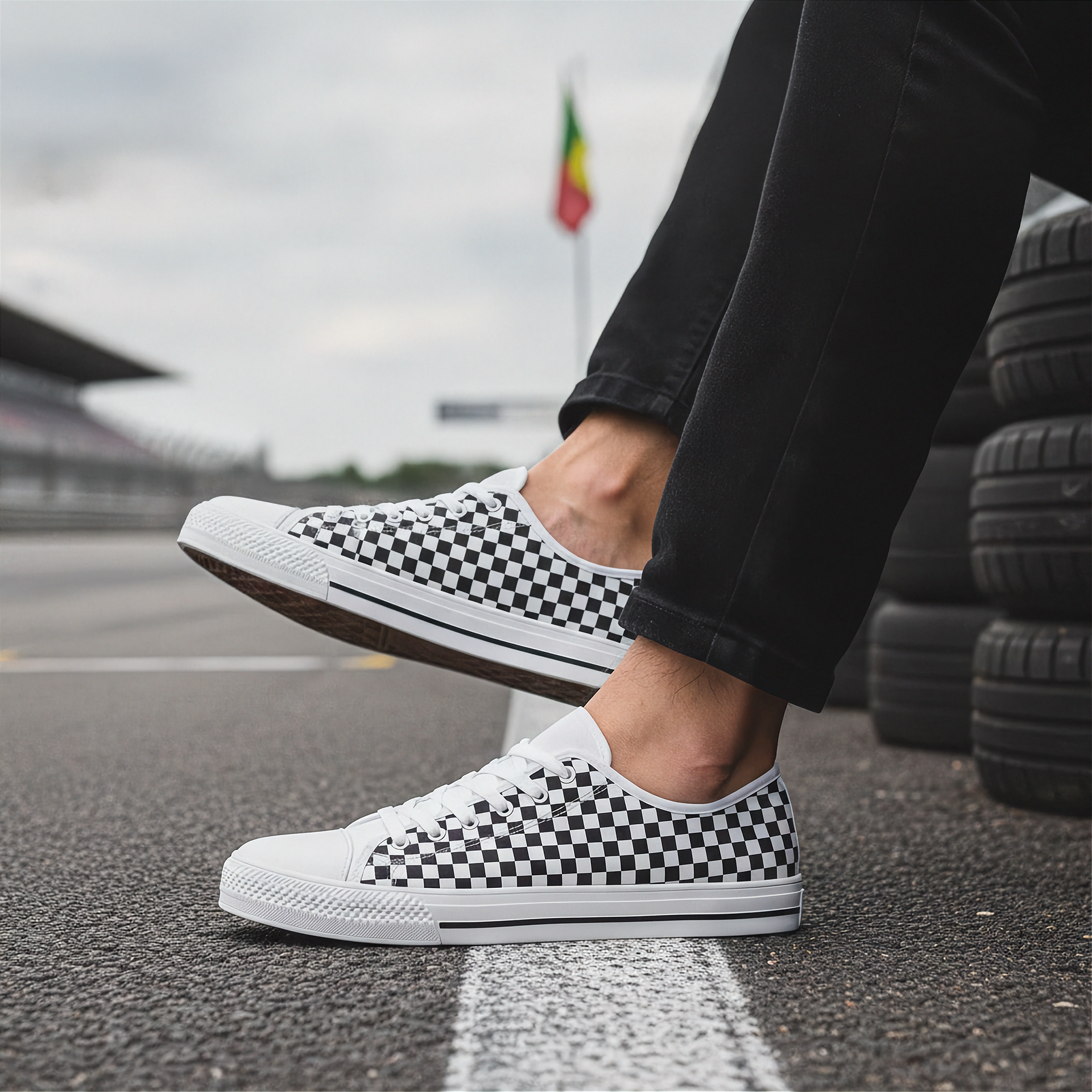 Person wearing white sneakers with black checkered pattern on a racetrack.