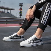 Person wearing black and white checkered sneakers with 'RACING' text on a racetrack.