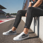 Person wearing checkered sneakers sitting on a race track.