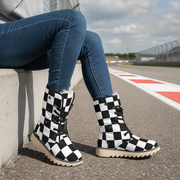Person wearing black and white checkered boots on a race track.
