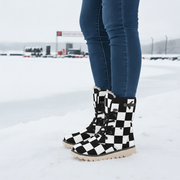 Black and white checkered boots worn with blue jeans on a snowy ground.