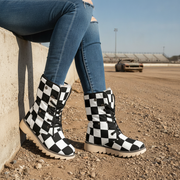 Person wearing black and white checkered boots with blue jeans on a race track.