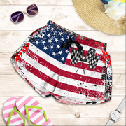 American flag patterned shorts with sunglasses, hat, and flip-flops on a wooden surface