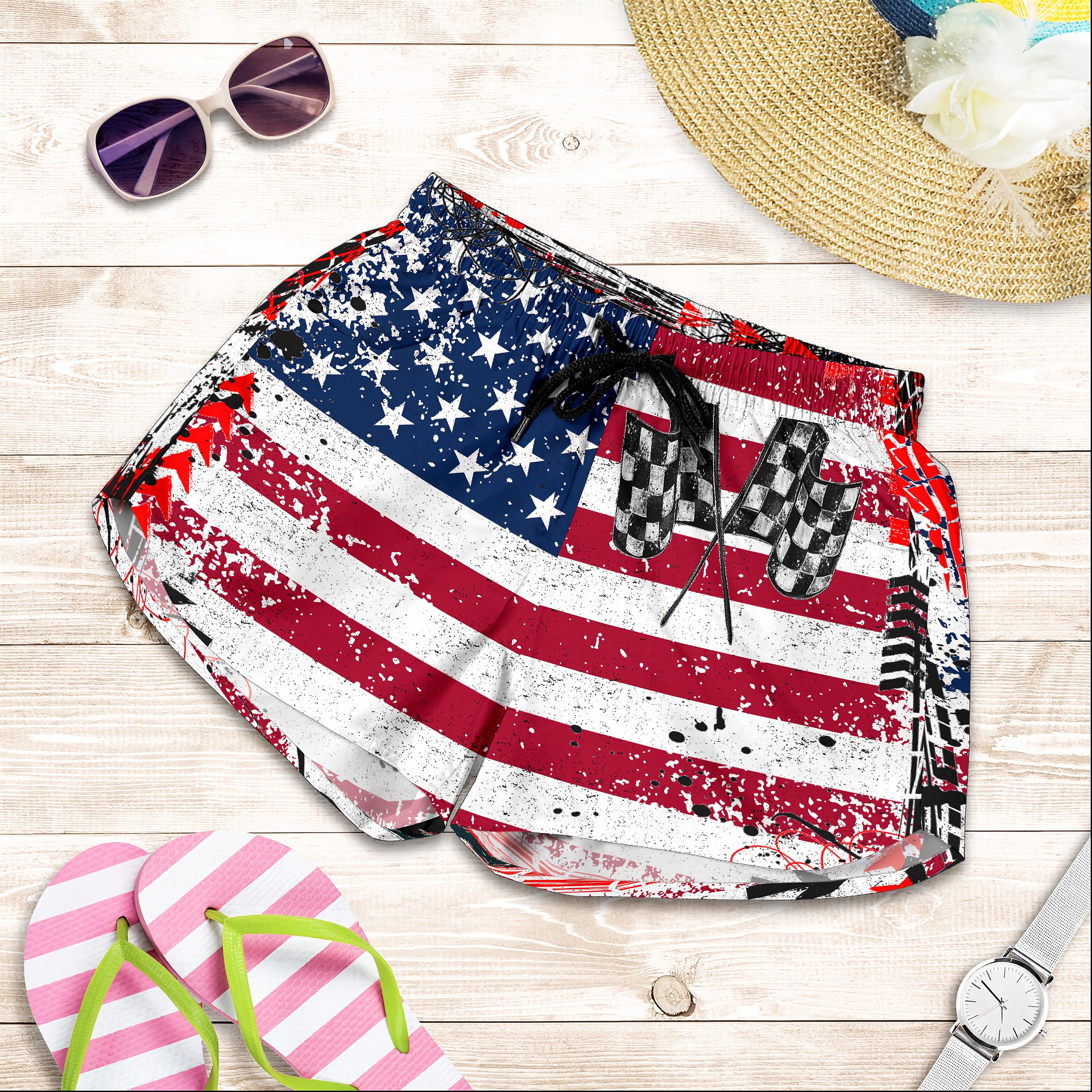 American flag patterned shorts with sunglasses, hat, and flip-flops on a wooden surface