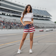 Woman wearing a white crop top and American flag shorts on a race track.