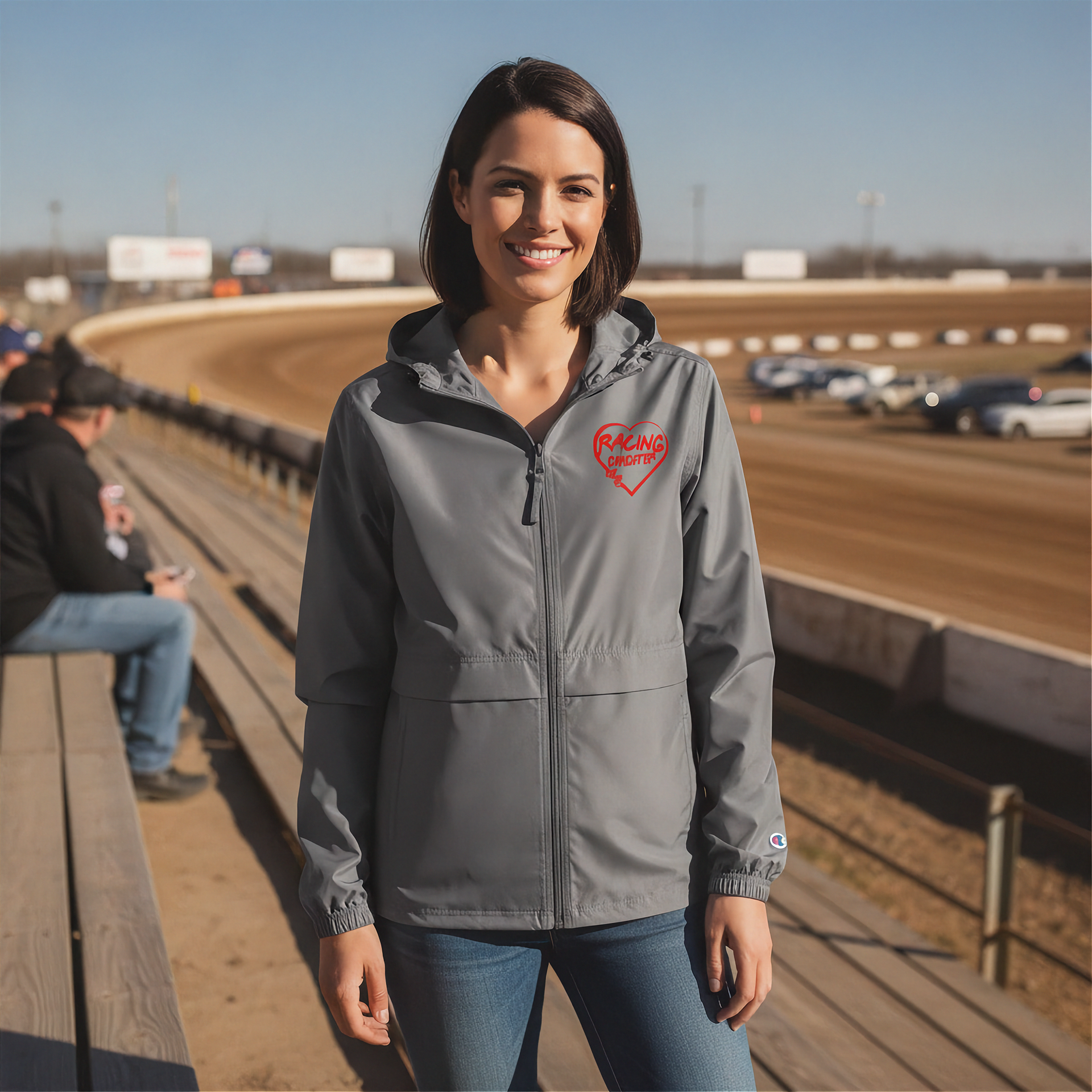 Woman wearing a gray jacket with a red racing daughter heart design at a race track