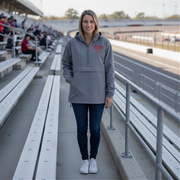 Woman wearing a gray hoodie with a red racing daughter heart design standing on bleachers at a sports venue.