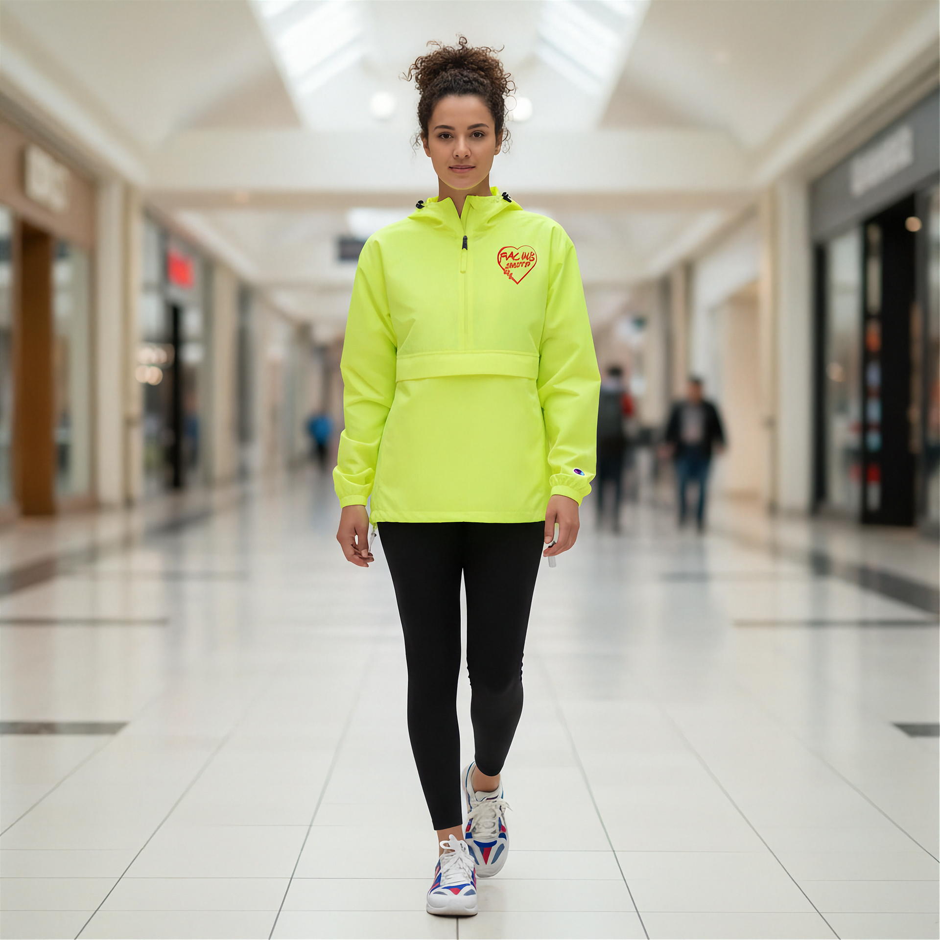 Woman wearing a bright yellow hoodie with a red racing daughter heart design in a mall setting