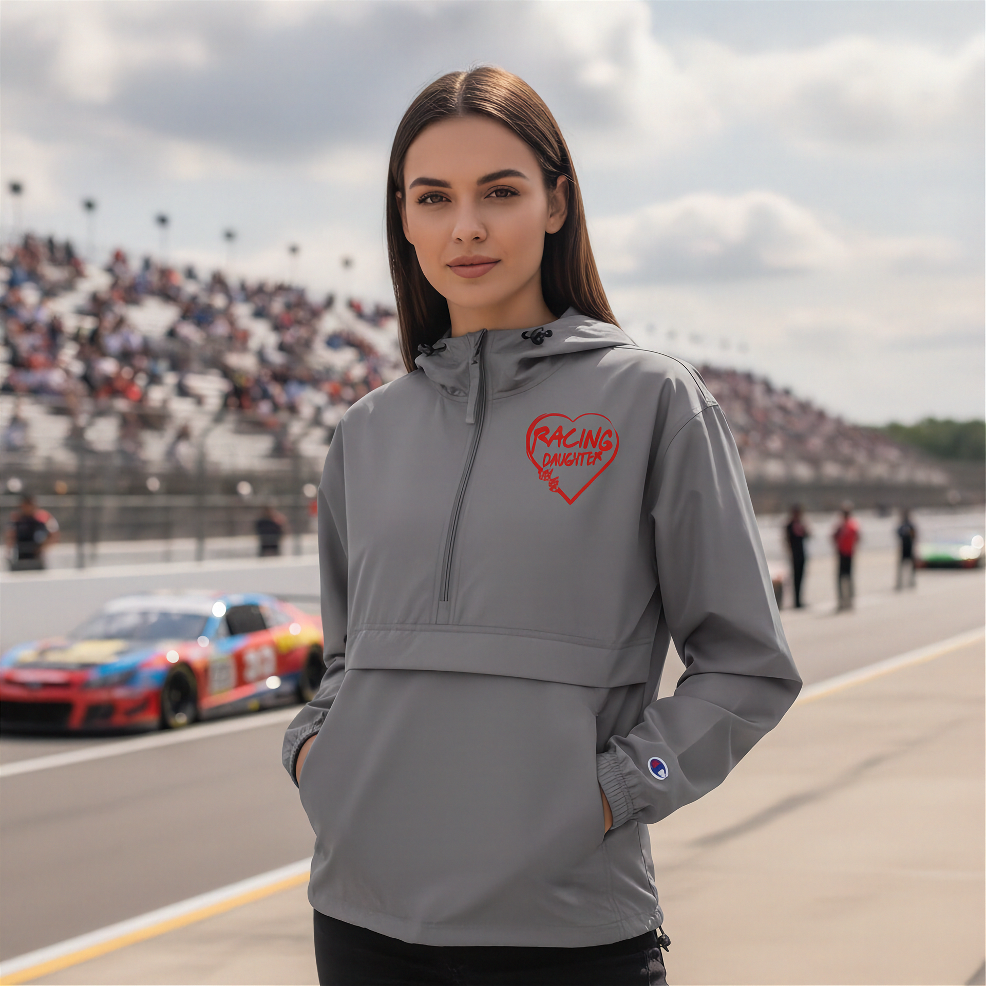 Woman wearing a gray jacket with a red racing daughter heart design on a race track