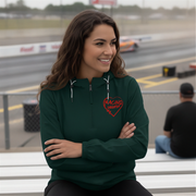 Woman wearing a green hoodie with a red racing daughter heart design on a race track background