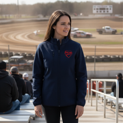 Woman wearing a navy blue jacket with a red racing daughter heart design at a race track.