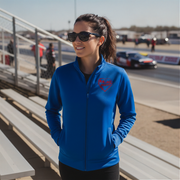 Woman wearing a blue jacket with a red racing daughter heart design at a race track.