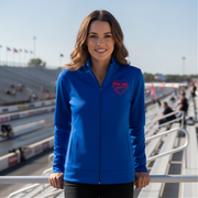 Woman wearing a blue jacket with a red racing daughter heart design at a race track.