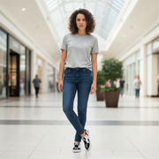 Woman wearing a gray t-shirt and blue jeans and checkered slip-on shoes standing in a shopping mall.