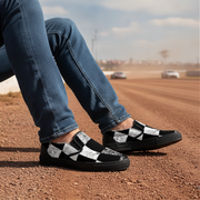 Man wearing black and white checkered shoes on a dirt surface with a blurred background