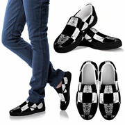 Black and white checkered slip-on shoes with glittery accents worn with blue jeans.