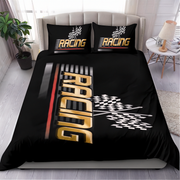 A black racing-themed bedding set on a bed in a styled bedroom, featuring a duvet cover and two pillowcases with gold 'RACING' text, checkered flags, and red and white graphic accents.