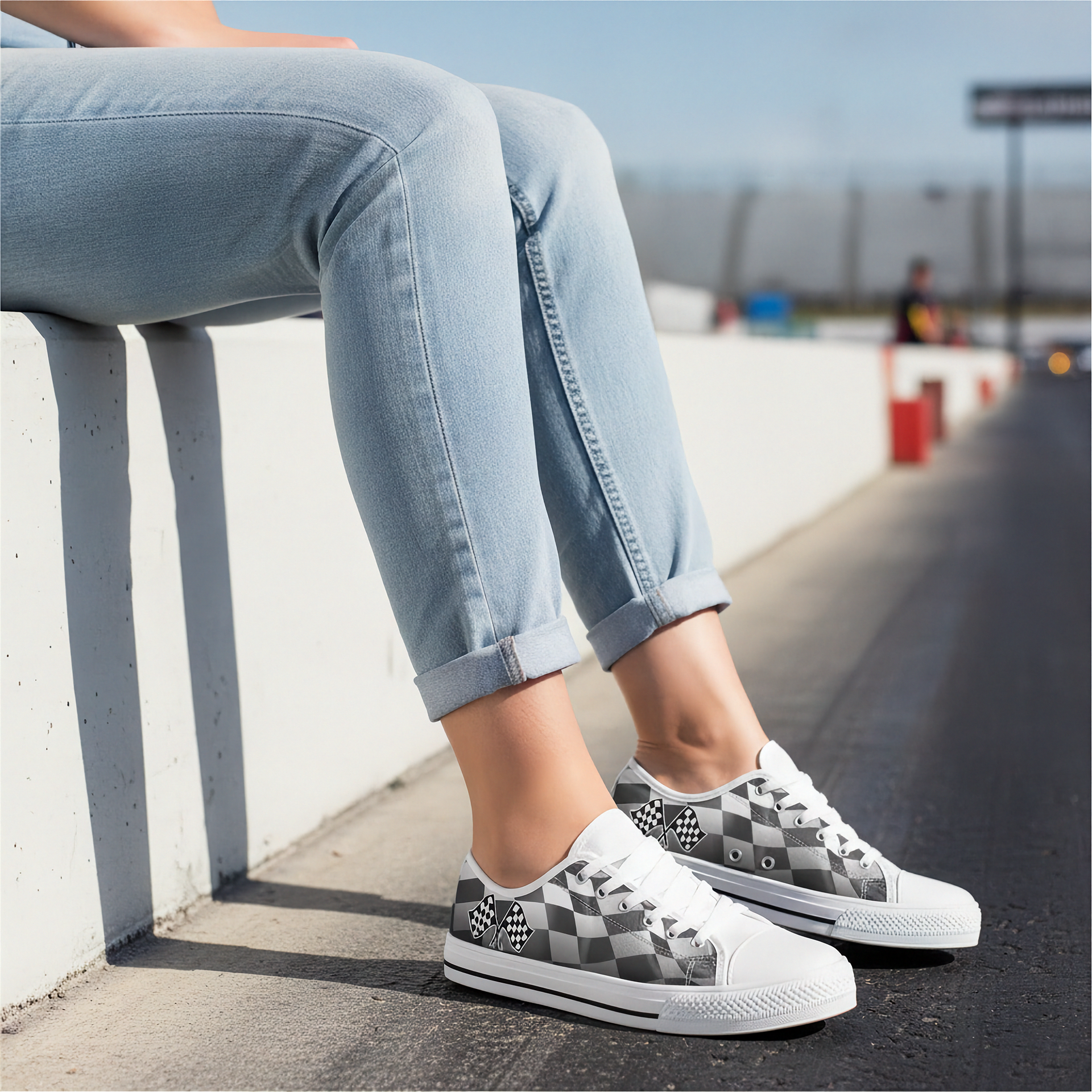 Person wearing checkered sneakers and light blue jeans sitting on a concrete ledge.