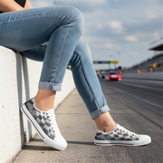 Woman wearing checkered shoes sitting on a curb with a race track in the background
